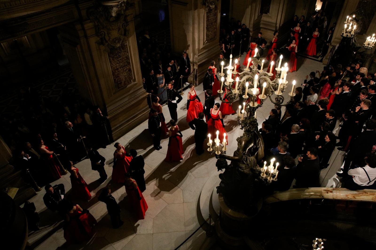 Le grand escalier du Palais Garnier pendant le Bal de l’X, invités en tenue de soirée sous les candélabres
